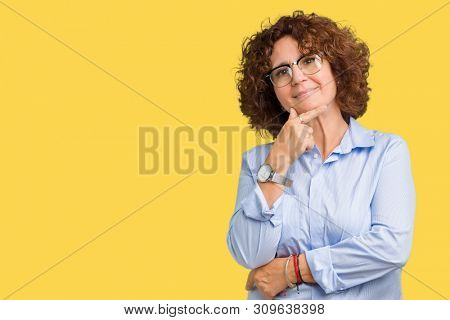 Beautiful middle ager senior businees woman wearing glasses over isolated background looking confident at the camera with smile with crossed arms and hand raised on chin. Thinking positive.