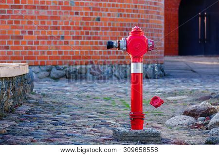 Red Fire Water Coming A Street Hydrant Near A Wall, Fire Hydrant Or Fireplug Connection For Firefigh