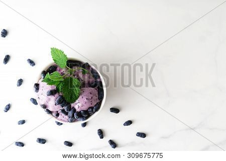 Ice-cream Decorated With Fresh Berries Of A Honeysuckle And Green Leaves On White Background. Top Vi