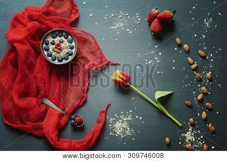 Breakfast With Love. Bowl Of Oatmeal With Fruit And Almonds On A Gray Table With Tulip And Red Scarf