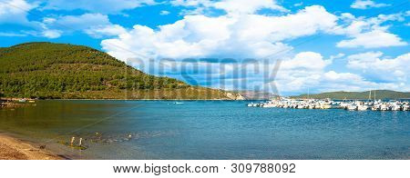 View Of Gulf, Pier And Beach Of Tramariglio In A Sunny And Cloudy Day, In The Capocaccia Coast