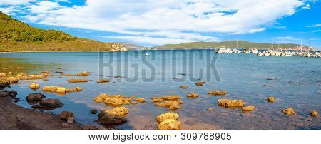 View Of Gulf, Pier And Beach Of Tramariglio In A Sunny And Cloudy Day, In The Capocaccia Coast