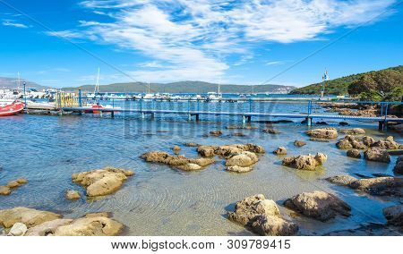 View Of Gulf, Pier And Beach Of Tramariglio In A Sunny And Cloudy Day, In The Capocaccia Coast