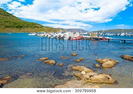View Of Gulf, Pier And Beach Of Tramariglio In A Sunny And Cloudy Day, In The Capocaccia Coast