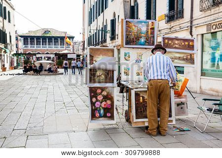 Venice, Italy - April, 2018: Senior Artist Selling His Paintings At The Santa Sofia Square In Venice