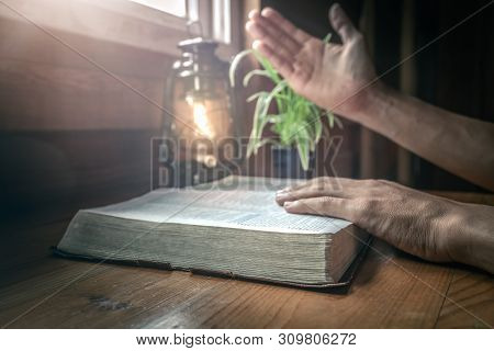 Close Up Beside Old The Holy Bible With Hands Of Christian Praying Background.