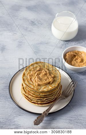 Vegan Pancakes With Flax Seeds, Peanut Butter And Vegan Milk On A White Plate On A Gray Background. 