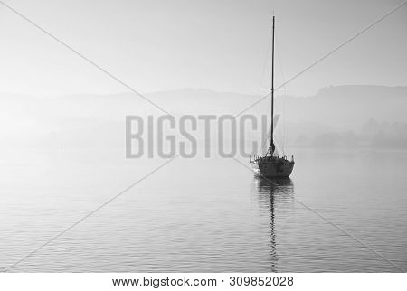 Beautiful Unplugged Landscape Image Of Sailing Yacht Sitting Still In Calm Lake Water In Lake Distri
