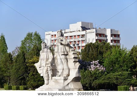 Pyongyang, North Korea - May 1, 2019: Heroic Statues In Park Nearby Juche Tower Show At Sunset Start