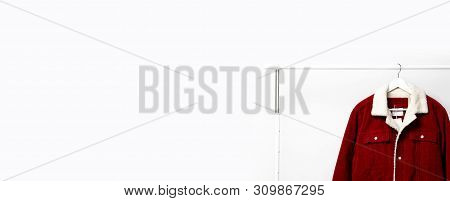 Red Corduroy Men's Jacket On White Coat Hanger On Rod Against Light Wall Flat Lay Copy Space. Male F