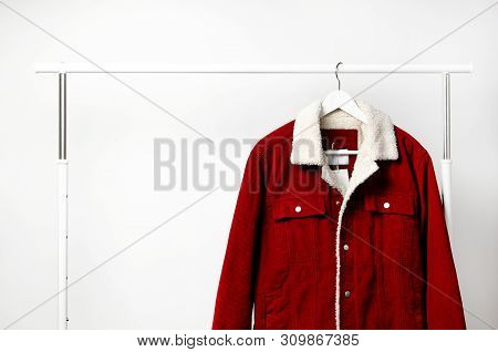 Red Corduroy Men's Jacket On White Coat Hanger On Rod Against Light Wall Flat Lay Copy Space. Male F