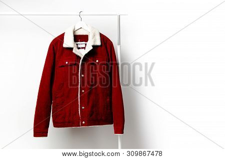 Red Corduroy Men's Jacket On White Coat Hanger On Rod Against Light Wall Flat Lay Copy Space. Male F