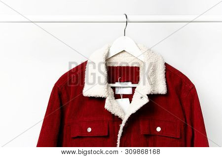 Red Corduroy Men's Jacket On White Coat Hanger On Rod Against Light Wall Flat Lay Copy Space. Male F