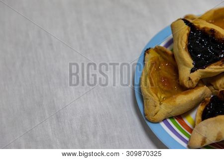 Hamantash Purim Blueberry And Apricot Jam Cookies On Colored Plate With White Sheet Background