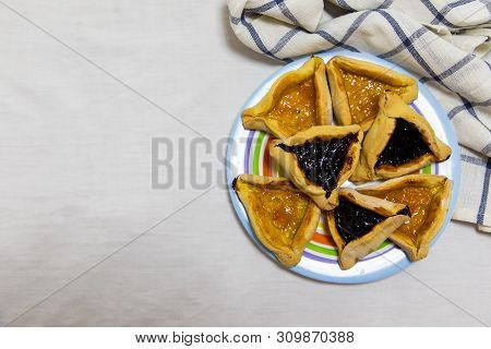Hamantash Purim Blueberry And Apricot Jam Cookies On Colored Plate With A Plaid Blue Rag And A White