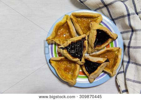 Hamantash Purim Blueberry And Apricot Jam Cookies On Colored Plate With A Plaid Blue Rag And A White
