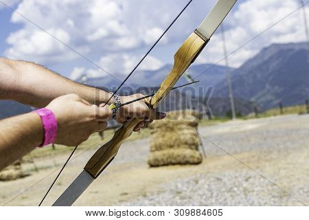 A Person With A Bow And An Arrow Aiming To Shoot A Bullseye.