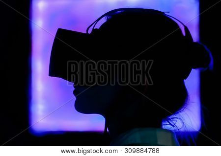 Woman Using Virtual Reality Headset And Looking Around At Interactive Technology Exhibition With Pur