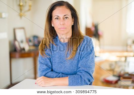 Beautiful middle age woman at home with serious expression on face. Simple and natural looking at the camera.