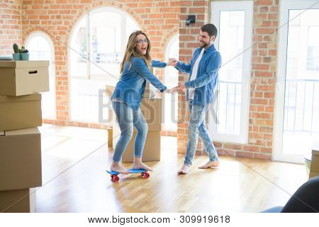 Young couple moving to a new home, having fun riding a skateboar