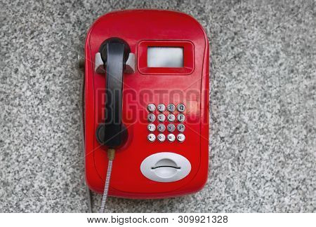 Red Metal Phone, Automatic, Payphone Hangs On The Wall On A City Street