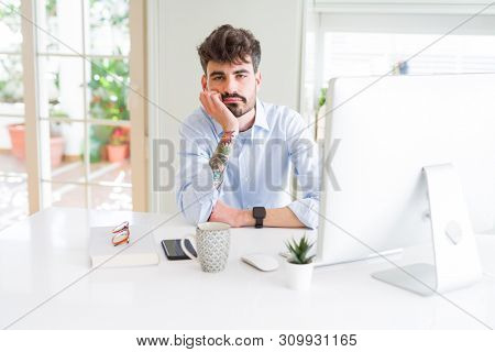 Young business man working using computer thinking looking tired and bored with depression problems with crossed arms.
