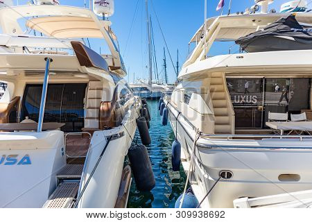 White Moored Luxury Yachts With Masts, In Contrast To Blue Calm Sea. Reflection Of Vessels, Sky Back