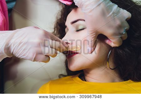 Depilation With Hot Wax Mustache In The Beauty Salon. Young Woman Receiving Facial Epilation Close U