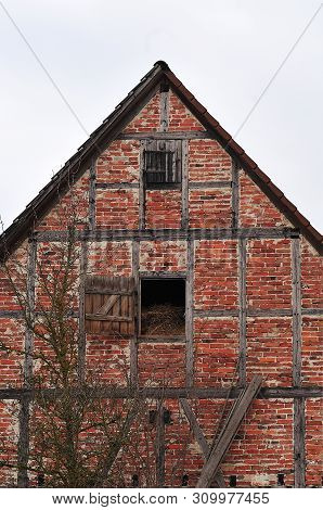 Half-timbered Facade Of Old Barn In A Village With Hay Stored In Attic