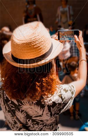 Tourist Girl Taking A Picture With A Smartphone Of Giants And Large Heads In Catalonia, Spain