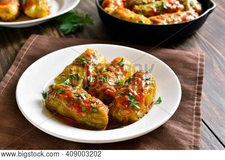 Cabbage Rolls Stuffed With Ground Beef, Rice And Baked With Tomato Sauce On Plate On Wooden Table. C