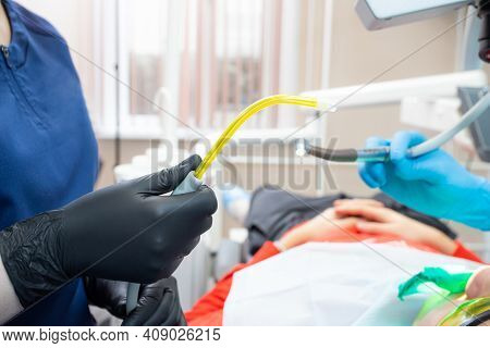 Dental Assistant Helping With Saliva Ejector During Dentist Treatment