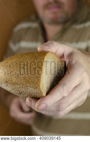 A Middle-aged Man With A Beard And Mustache Holds Out Half A Loaf Of Rye Bread To The Cell. Mercy, D