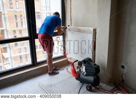 Back View Of Plumber Filling Pipes With Pressurized Air To Inspect For Leaks In New Installation Of 