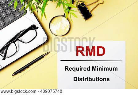 Rmd Required Minimum Distributions Is Written In Red On A White Piece Of Paper On A Light Yellow Bac