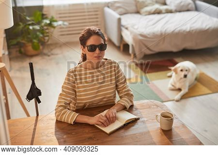 Warm Toned High Angle Portrait Of Modern Blind Woman Reading Braille Book While Sitting At Table In 