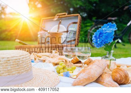 Summer Picnic On Sunny Day With Bread, Fruit, Bouquet Hydrangea Flowers, Glasses Wine, Straw Hat, Bo