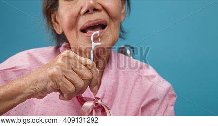 Caregiver Take Care Asian Elderly Woman While Using Dental Fross Stick.