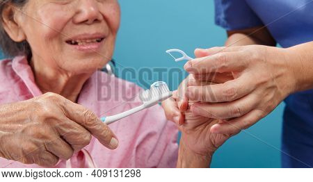 Caregiver Take Care Asian Elderly Woman While Using Dental Fross Stick.