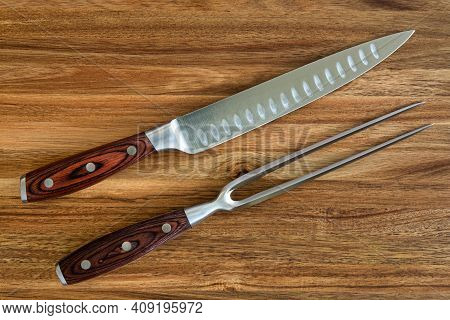 Photograph Of Knife And Fork Carving Set On A Wood Cutting Board