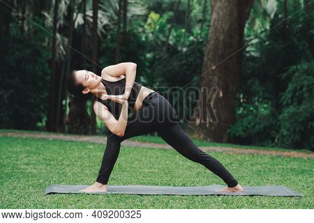 Asian Woman Practicing Yoga In Prep Poses For Side Crane Pose For Parsva Bakasana On The Mat In Outd
