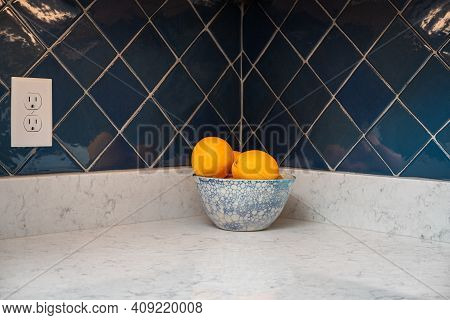 Oranges In A Blue And White Bowl On A Granite Counter With A Blue Tile Backsplash