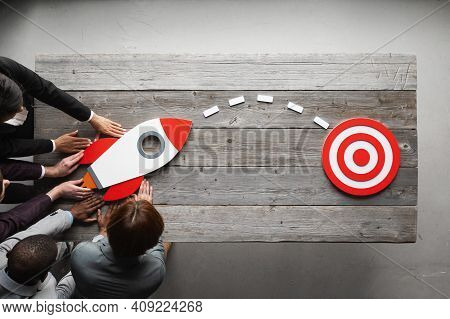Team Of Business People With Rocket As A Sumbol Of High Risky Goals Targeting At Red Target At Meeti