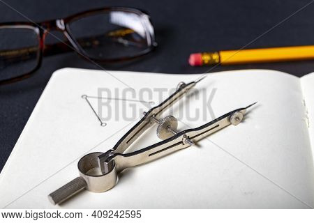 A Metal Circinus Arranged On A Notebook. Accessories For Drawing In A Design Office.