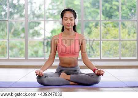 Asian Woman Practice Yoga Meditation Exercise  With Headphones At Home, Young Asia Female Sitting On