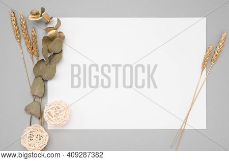 White Invitation Card Mockup With A Dried Eucalyptus And Golden Ears Decoration On A Neutral Table. 