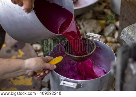 Process Of Straining Grape Juice For Wine. A Sieve And Two Pans Of Metal. View From Above.