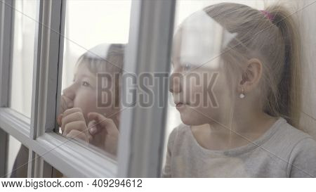 Little Children Boy And Girl Standing Behind The Door With Glass Inserts. Action. Sister And Brother