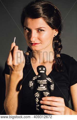 Empowered Furious Young Woman Holding A Voodoo Doll And A Needle