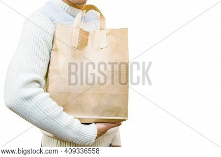 Blank Brown Paper Bag With Handles In Men's Hand In A White Sweater, Isolated On A White Background.